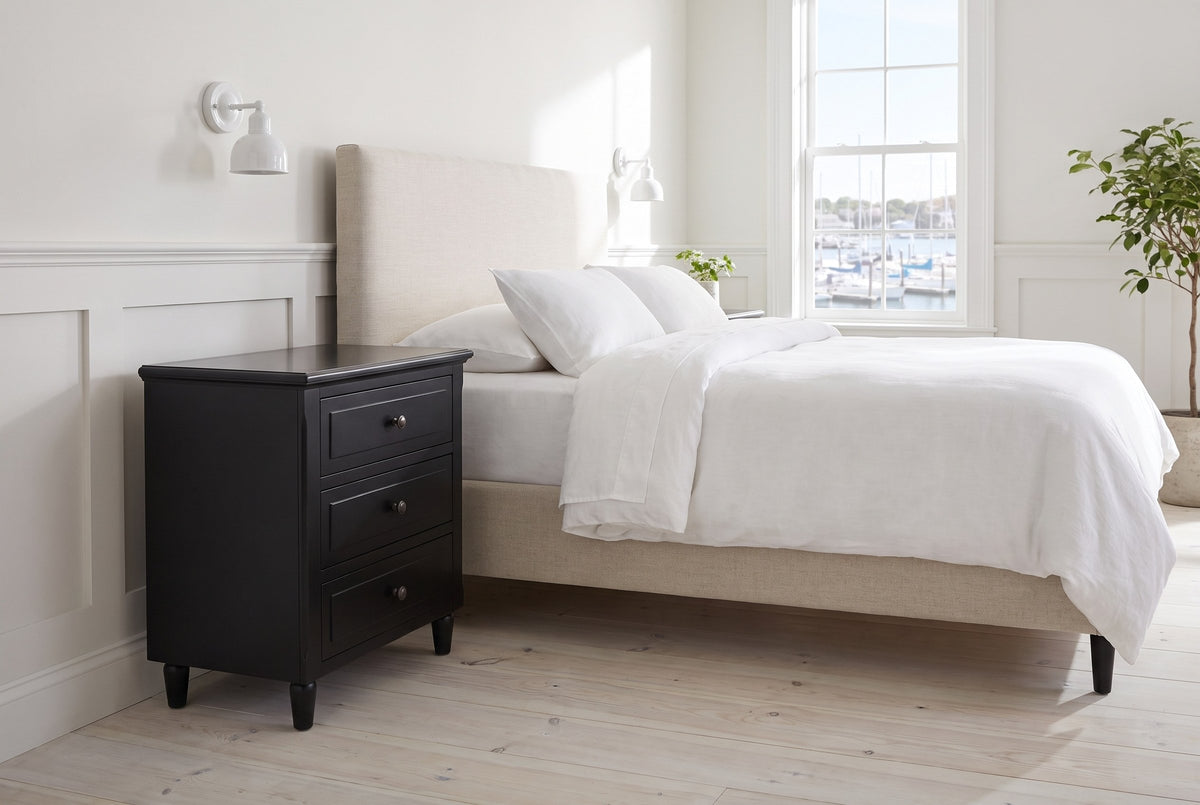 Ortona nightstand in Black beside a bed with white linen in a bright Halifax bedroom with a harbour view