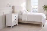 Ortona nightstand in White beside a bed with white linen in a bright Halifax bedroom with a harbour view