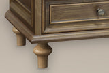 Close-up of the stepped plinth and two turned pine legs of the Osimo nightstand in Light Brown