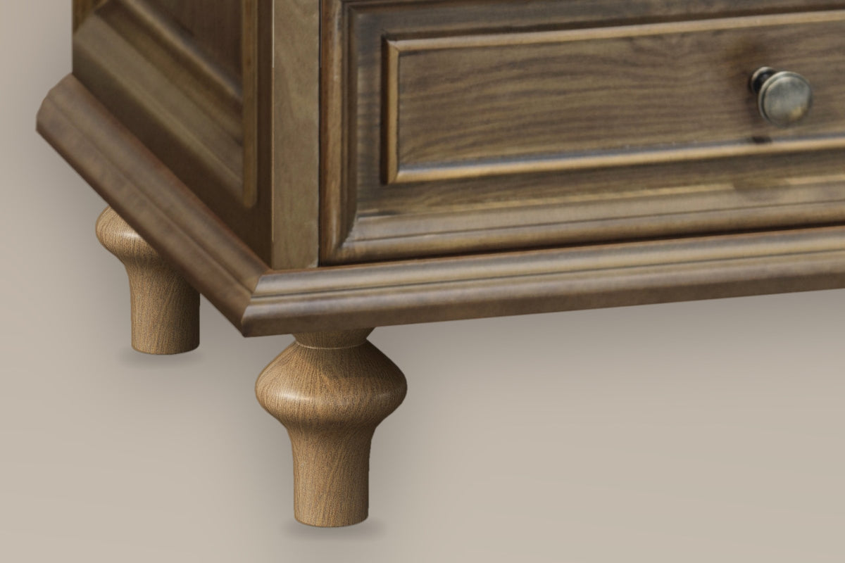 Close-up of the stepped plinth and two turned pine legs of the Osimo nightstand in Light Brown