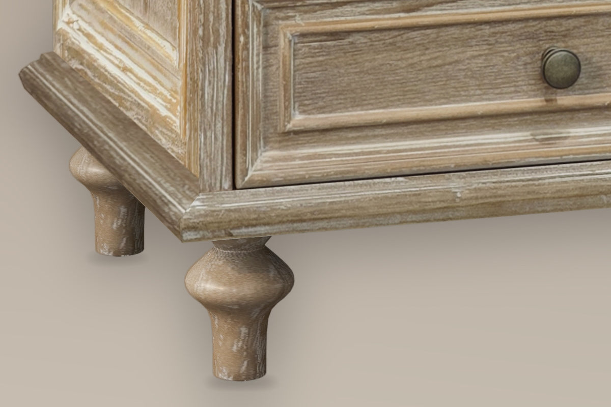 Close-up of the stepped plinth and two turned pine legs of the Osimo nightstand in Natural White