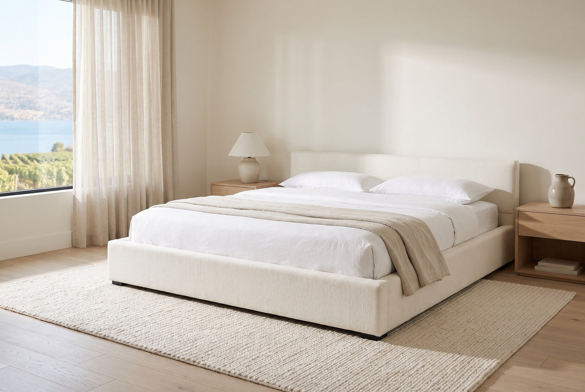 Otranto bed made up with white linen in a bright bedroom with pale oak nightstands and a window onto a lake and vineyards