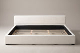 Otranto bed, straight front view: a low padded headboard and a wide upholstered rim on black block feet