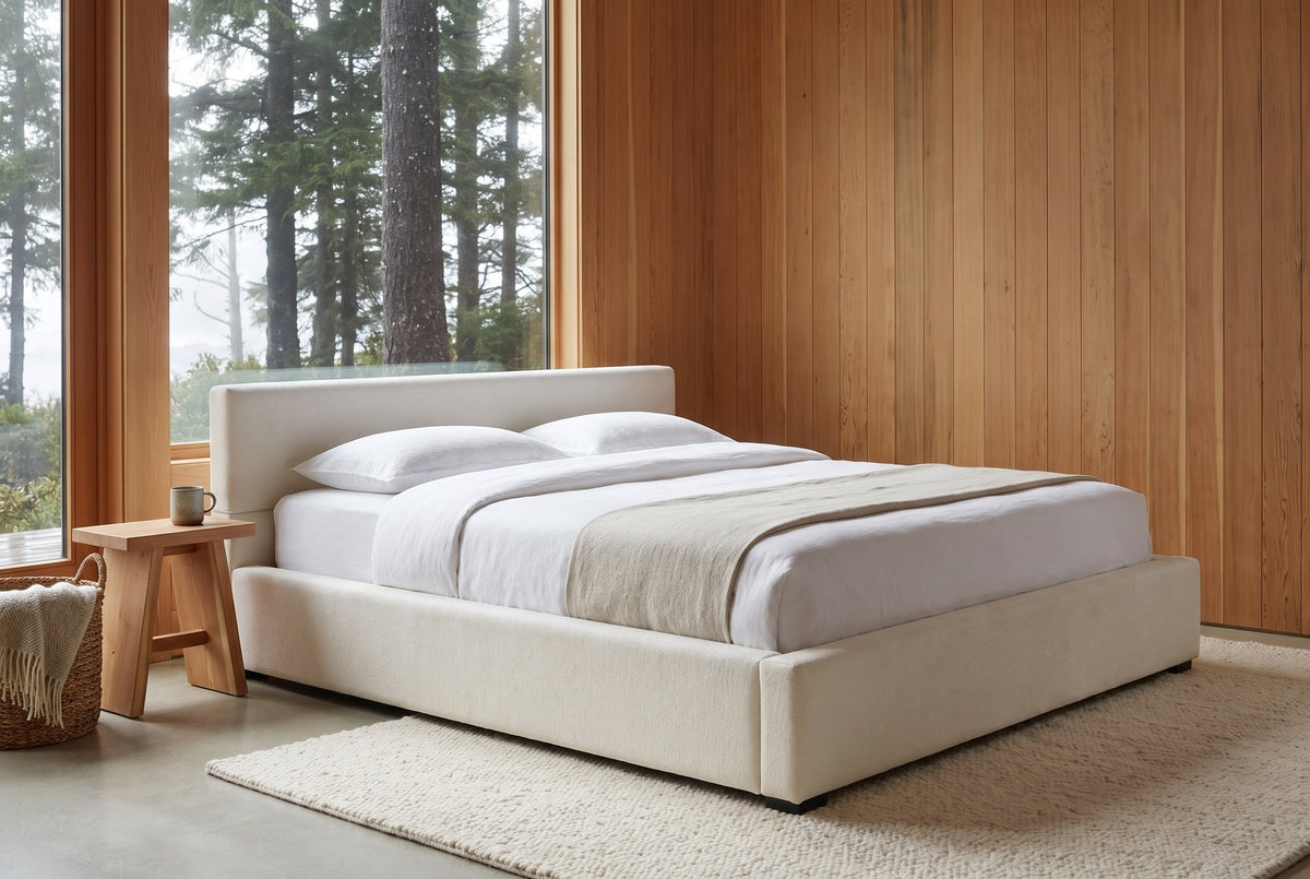 Otranto bed in a cedar-panelled bedroom with a tall window onto misty evergreens and a cedar stool beside it