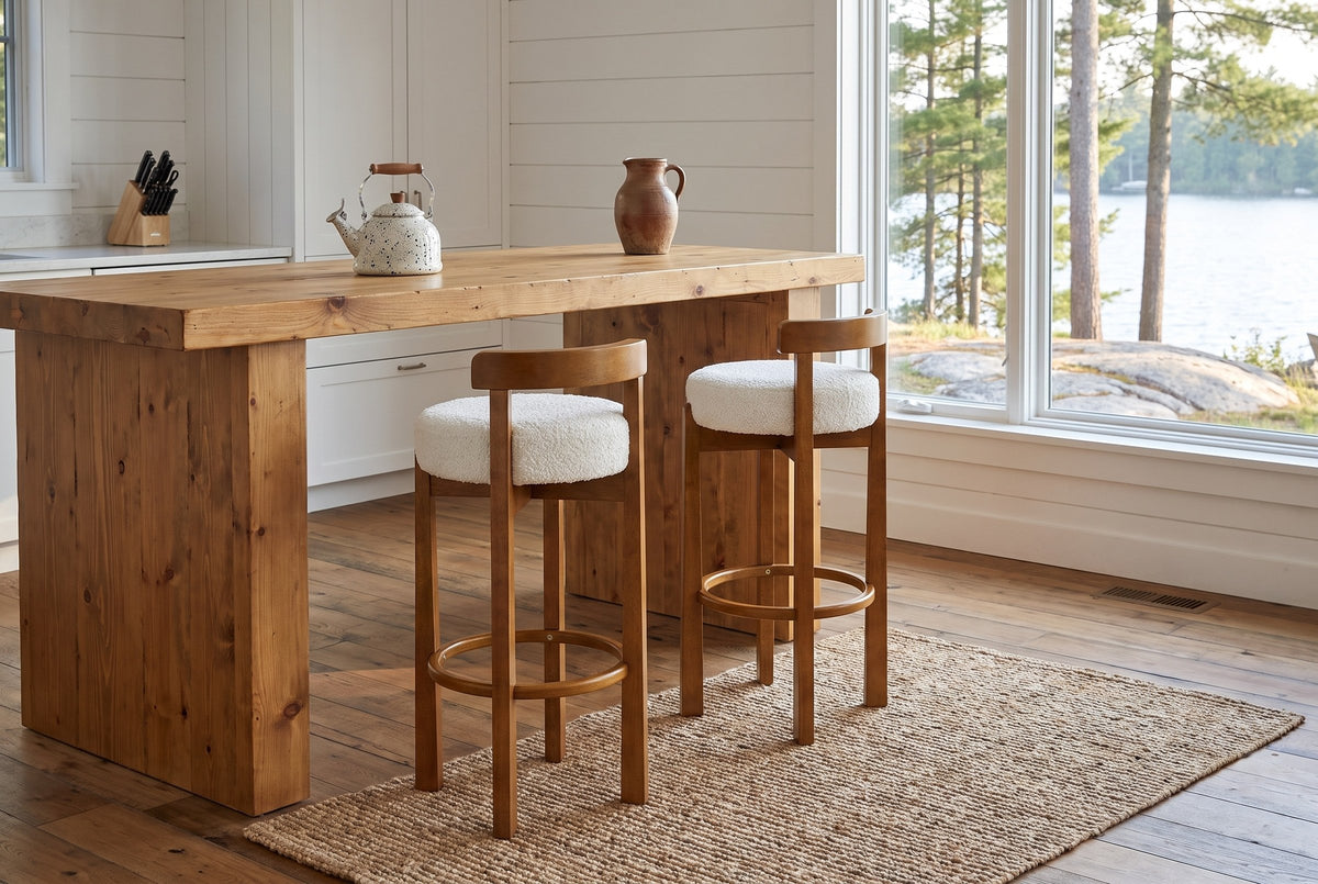 Two Otricoli bar stools at a pine-plank island in a Muskoka cottage kitchen with a window onto the lake