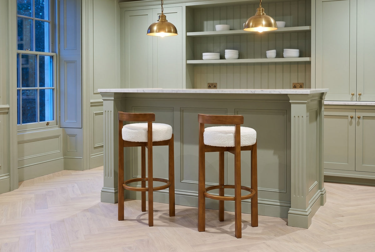 Two Otricoli bar stools at a sage-green panelled home bar with a marble top and brass pendant lamps in a Toronto townhouse