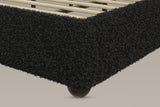 Close-up of the black teddy foot corner of the rail, the pale slats inside it and a dark ball foot