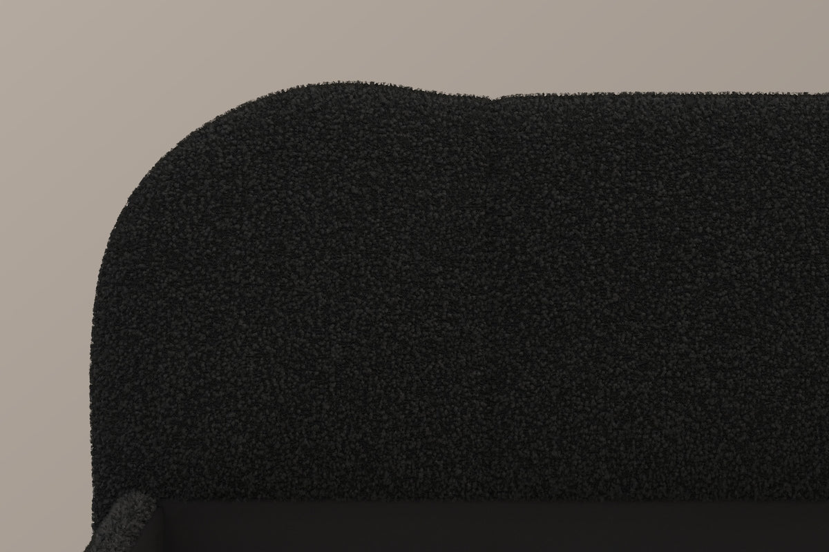 Close-up of the black teddy bouclé headboard: its big rounded corner and the soft bump where two panels meet