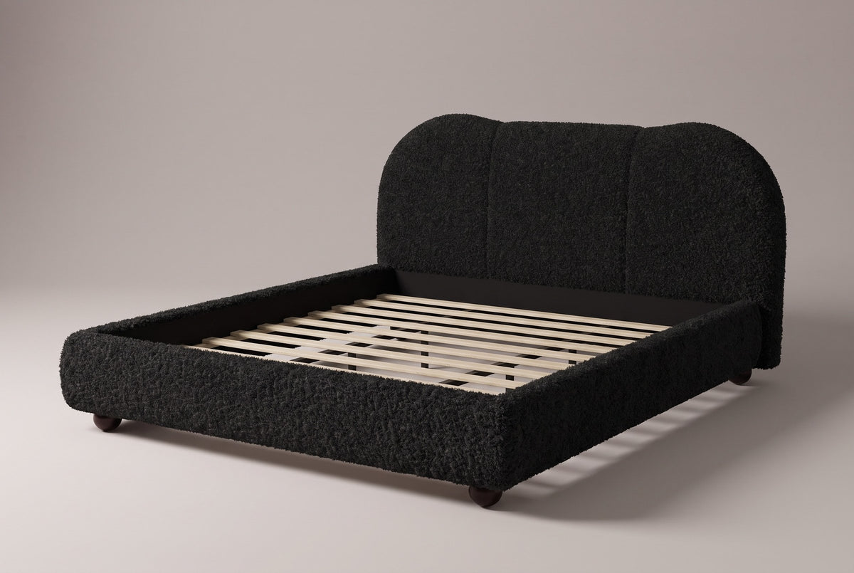 Padula cloud bed in black teddy bouclé, three-quarter view on a warm light-grey studio backdrop