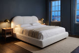 Padula bed in a slate-blue bedroom at dusk, brass lamps lit and harbour lights in the window