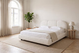 Padula bed in white made up with white linen, in a bright bedroom with an arched window and a fiddle-leaf fig