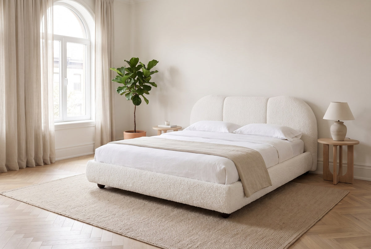 Padula bed in white made up with white linen, in a bright bedroom with an arched window and a fiddle-leaf fig