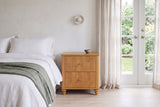 Palestrina nightstand in Natural beside a white linen bed in a bright Victoria bedroom with French doors to the garden