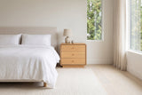 Parma nightstand beside a bed in white linen, in a bright Vancouver bedroom in morning light