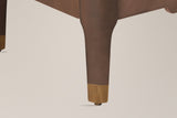 Close-up of a Pavia corner post running into a tapered leg with a gold-tone cap and a floor glide