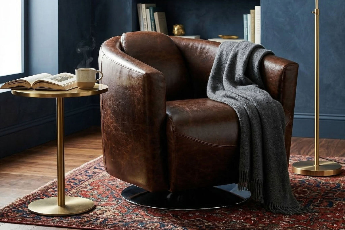 Percival brown bi-cast leather club chair with a grey throw beside a brass floor lamp and bookshelf