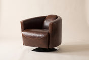 Percival swivel club chair in Brown, three-quarter view on a warm off-white studio backdrop: a rounded barrel back flowing