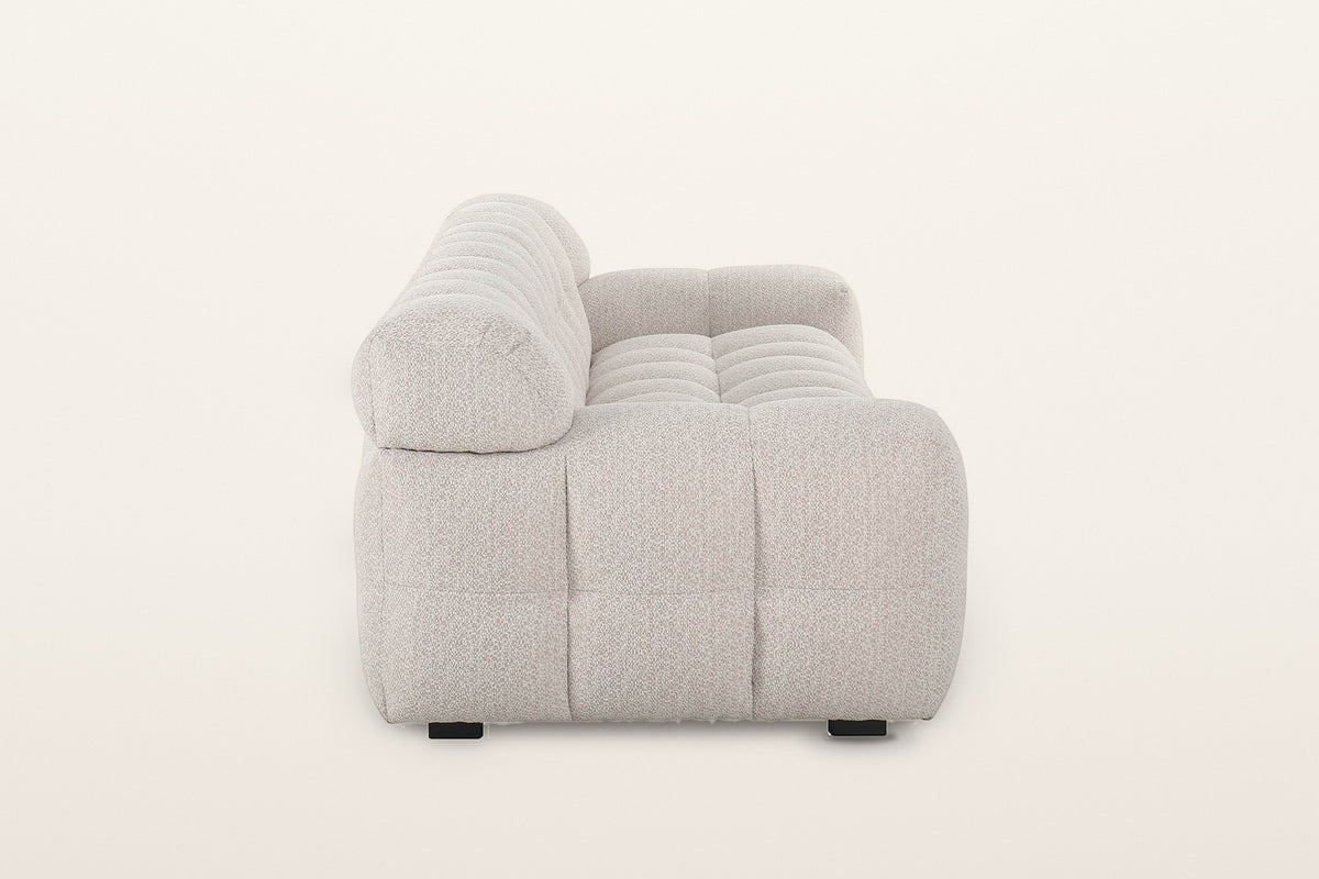 Pergola sofa in Beige, side view on a warm white studio backdrop: a round roll at the end of the back above the low puffed ar