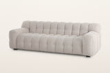 Pergola sofa in Beige, three-quarter view on a warm white studio backdrop: one body of rounded puffs