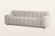 Pergola sofa in Beige, three-quarter view on a warm white studio backdrop: one body of rounded puffs