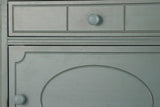 Close-up of the Perugia nightstand in Aged Blue: the drawer front with three routed panels and a round knob painted to match