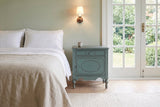 Perugia nightstand in Aged Blue beside a bed in a sage-green Victoria bedroom with French doors to the garden