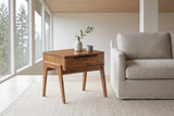 Pescasseroli end table in Brown acacia beside a stone linen sofa in a North Vancouver post-and-beam living room, firs through the window