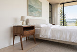 Pescasseroli nightstand in Brown acacia beside an oatmeal upholstered bed in a bedroom in a Courtenay estuary house