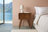 Side view of the Pescasseroli nightstand in Brown acacia in a bedroom in a Lugano lakeside villa