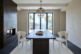 End view down a dark elm table with two Petralia dining chairs in Beige tweed in a Biarritz cliff villa