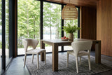 Two Petralia dining chairs in Beige tweed at the corner of a square smoked-oak table in a Haliburton forest house