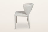 Petralia dining chair in Beige tweed, side view on a warm white studio backdrop: the back leans back and the rear legs rake o