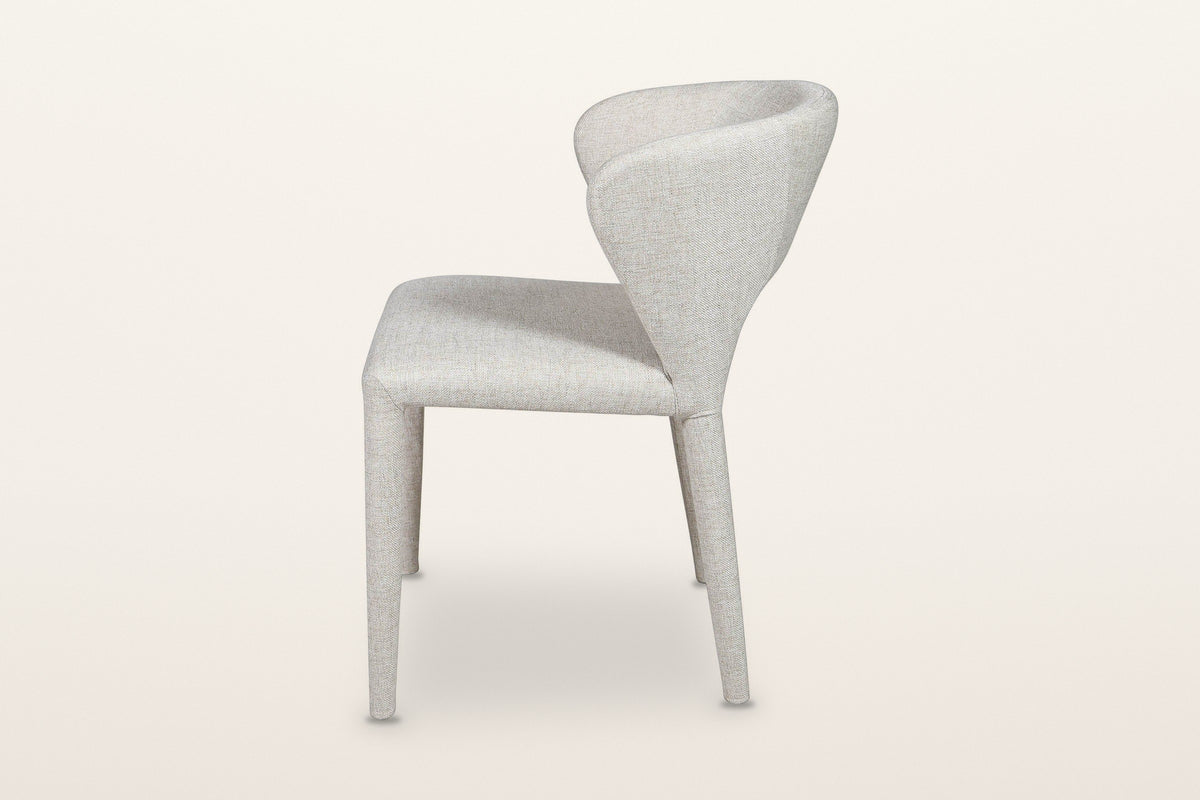 Petralia dining chair in Beige tweed, side view on a warm white studio backdrop: the back leans back and the rear legs rake o