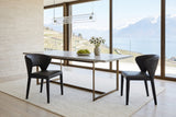 Two Petralia dining chairs in Black leather at the corner of a limestone table on a bronze frame in a Montreux villa