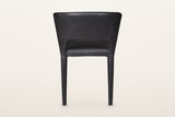 Back of the Petralia dining chair in Black leather on a warm white studio backdrop: a smooth wrapped shell with a low slot ab