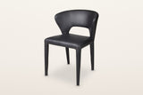 Petralia dining chair in Black leather, three-quarter view on a warm white studio backdrop