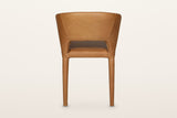 Back of the Petralia dining chair in Brown leather on a warm white studio backdrop: a smooth wrapped shell with a low slot ab