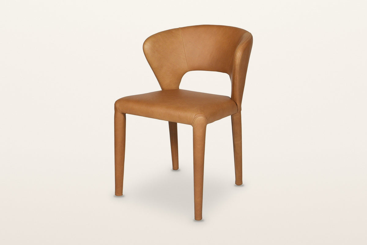 Petralia dining chair in Brown leather, three-quarter view on a warm white studio backdrop