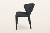 Petralia dining chair in Dark Grey, side view on a warm white studio backdrop: the back leans back and the rear legs rake out