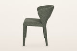 Petralia dining chair in Green, side view on a warm white studio backdrop: the back leans back and the rear legs rake out