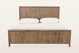 Pettorano bed, front view from the foot on a warm white studio backdrop: the low reeded footboard and the tall reeded headboa