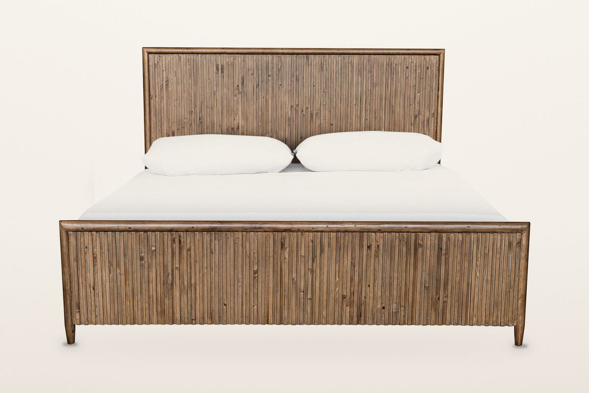 Pettorano bed, front view from the foot on a warm white studio backdrop: the low reeded footboard and the tall reeded headboa
