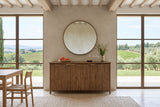 Pettorano sideboard in Brown, front view, against a greige plaster wall with a round bronze mirror in a Montalcino villa