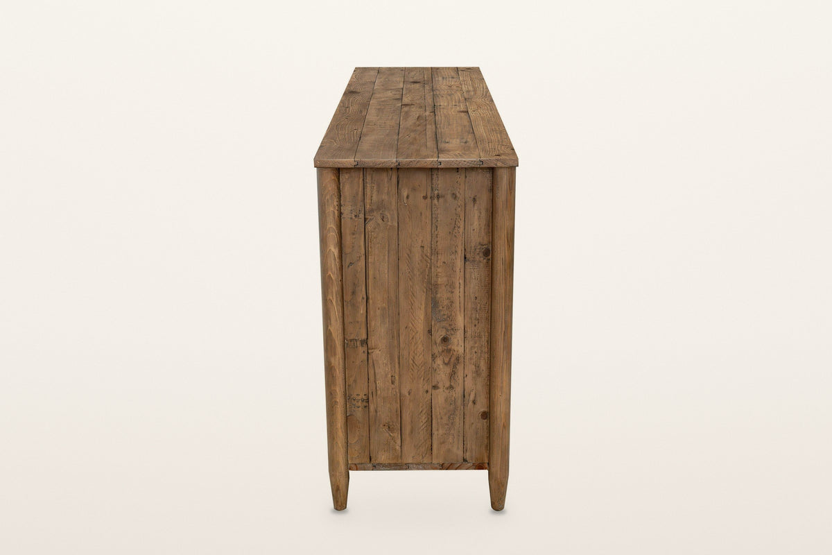 Pettorano sideboard in Brown, end view on a warm white studio backdrop: a planked pine end between two round posts on tapered