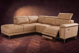The Pista sectional in Washed Sand distressed full leather on a dark walnut herringbone floor against a brown plaster wall, the seat beside the box arm reclined with its two-tier footrest out and its headrest raised, the other headrests down. Shown in Washed Sand, Left chaise.