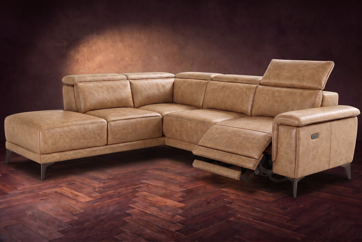 The Pista sectional in Washed Sand distressed full leather on a dark walnut herringbone floor against a brown plaster wall, the seat beside the box arm reclined with its two-tier footrest out and its headrest raised, the other headrests down. Shown in Washed Sand, Left chaise.