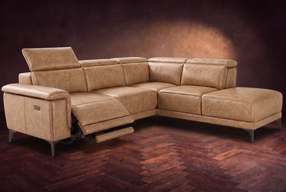 The Pista sectional in Washed Sand distressed full leather on a dark walnut herringbone floor against a brown plaster wall, the seat beside the box arm reclined with its two-tier footrest out and its headrest raised, the other headrests down. Shown in Washed Sand, Right chaise.