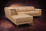 The Pista sectional in Washed Sand distressed full leather on a dark walnut herringbone floor against a brown plaster wall, seen from the chaise end, headrests down and footrest closed. Shown in Washed Sand, Left chaise.