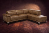 The Pista sectional in Weathered Saddle distressed full leather on a dark walnut herringbone floor against a brown plaster wall, three-quarter view from the arm end, headrests down and footrest closed. Shown in Weathered Saddle, Right chaise.