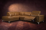 The Pista sectional in Weathered Saddle distressed full leather on a dark walnut herringbone floor against a brown plaster wall, the seat beside the box arm reclined with its two-tier footrest out and its headrest raised, the other headrests down. Shown in Weathered Saddle, Left chaise.